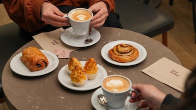Dos personas tomando café con piezas de pastelería en Shell Select.