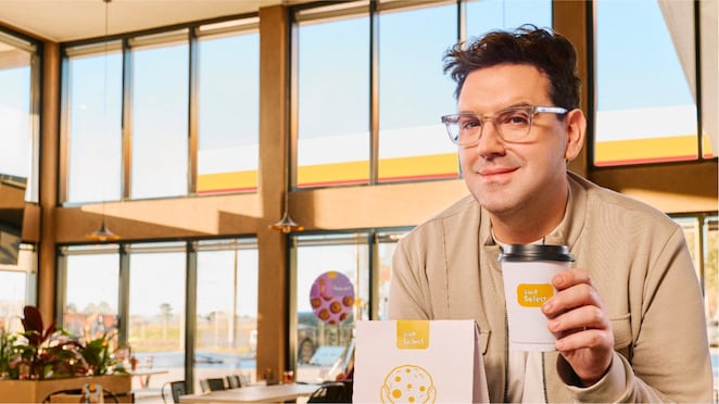 Betular sosteniendo una taza de café Shell Select.
