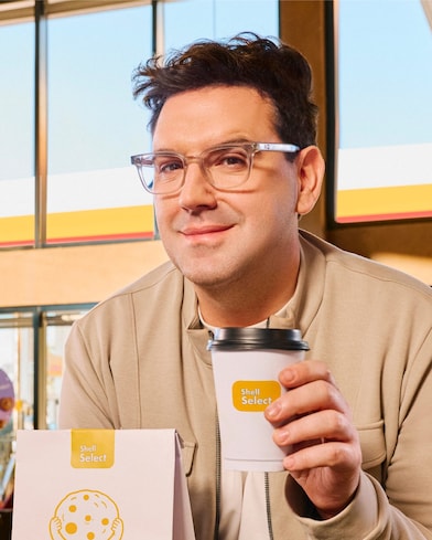 Betular sosteniendo una taza de café Shell Select.