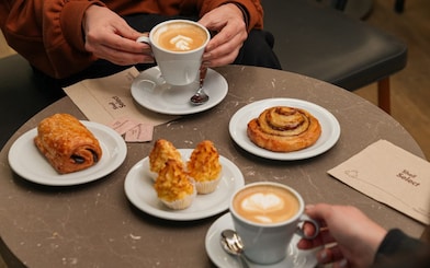 Dos personas tomando café con piezas de pastelería en Shell Select.