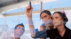 Businesswoman drawing graphs on glass