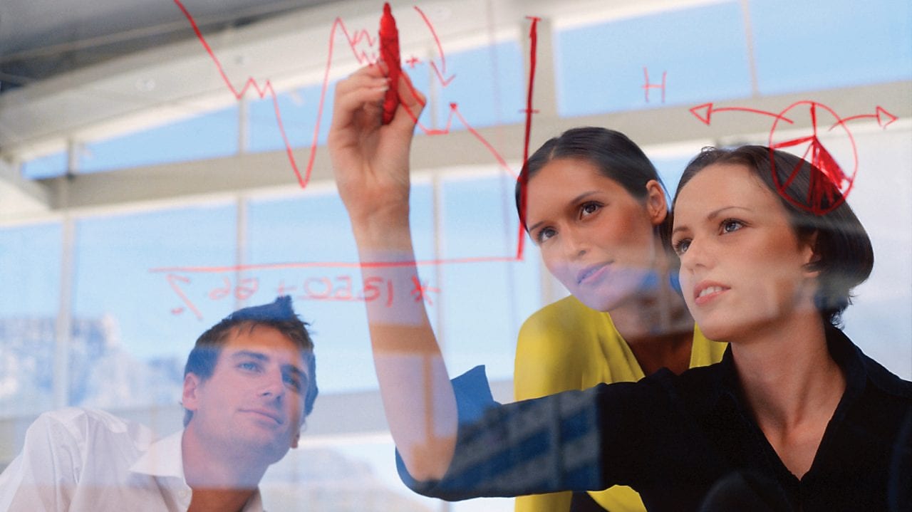 Mujer de negocios dibujando gráficos en una pizarra transparente