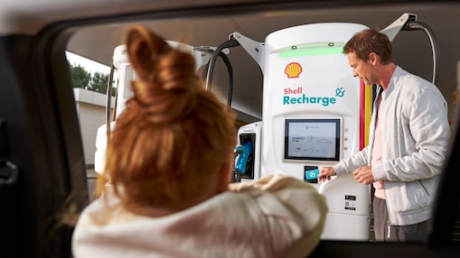 Un hombre usa una unidad de Recarga Shell mientras una niña mira desde el interior de un automóvil