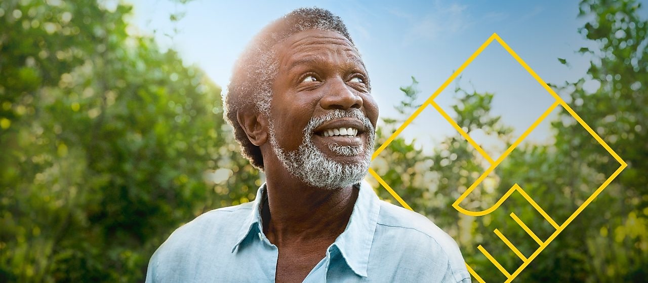 Hombre sonriente con barba frente a árboles con un gráfico de Generando valor para los accionistas