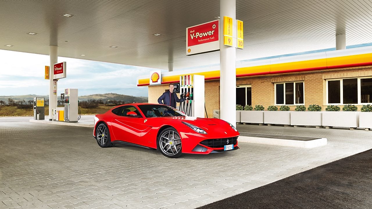 Carro Ferrari rojo en una estación de servicio Shell