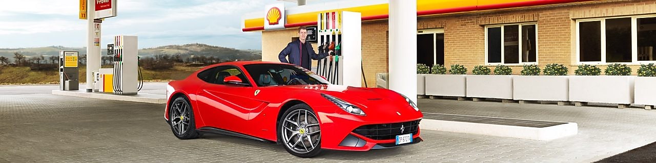 Carro Ferrari rojo en una estación de servicio Shell