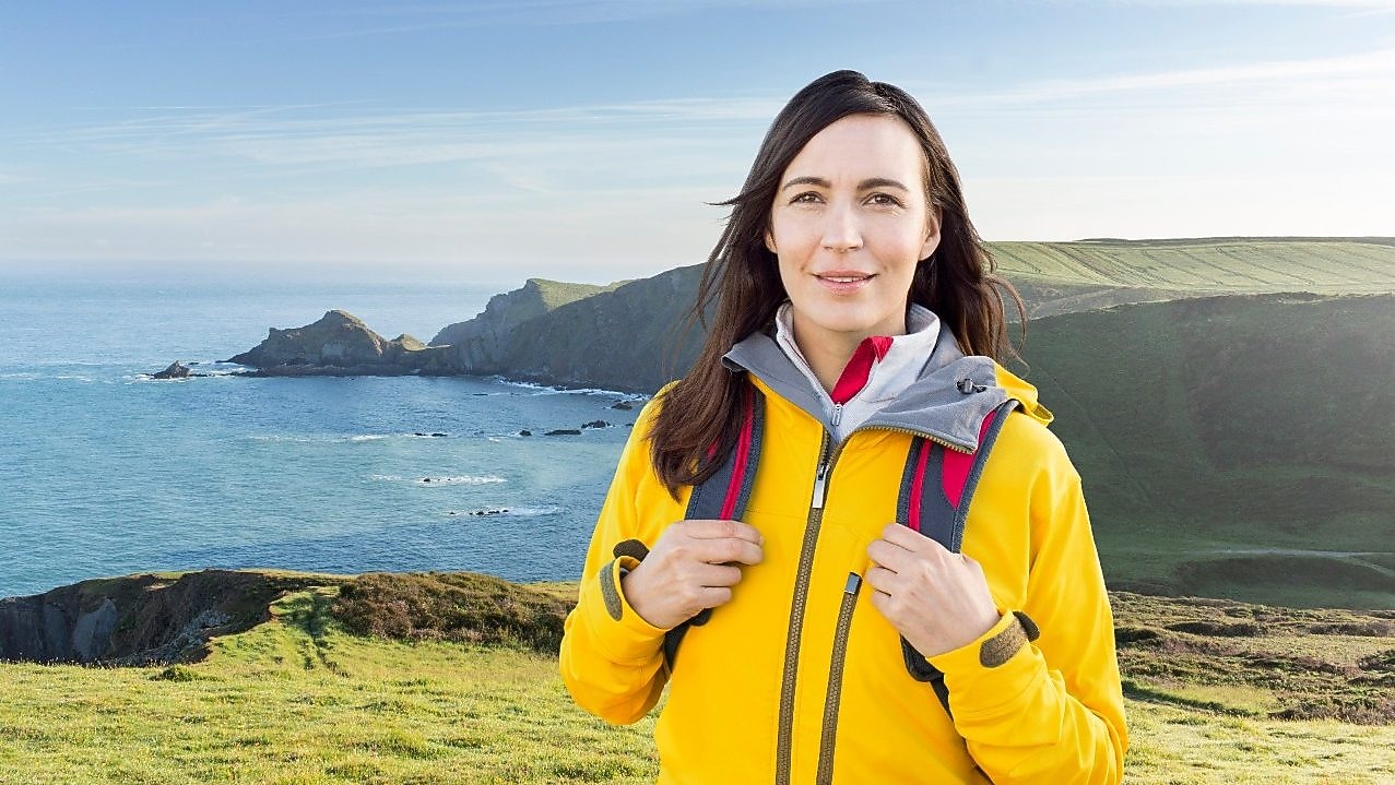 Mujer de pie en la montaña con unas bolsas