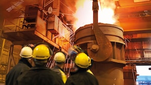 trabajadores mirando maquinaria pesada en una planta de procesamiento de metales