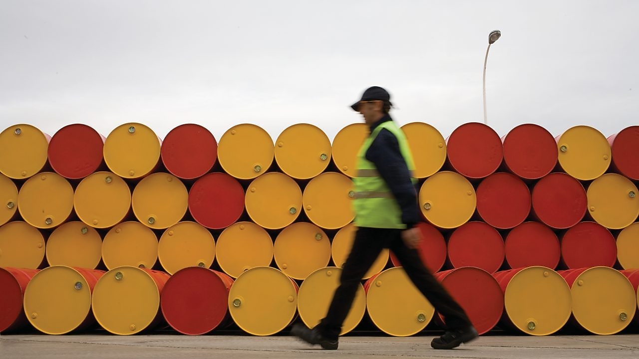 hombre caminando al lado de barriles de lubricantes