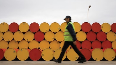 hombre caminando al lado de barriles de lubricantes