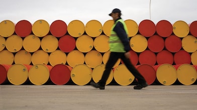 hombre caminando al lado de barriles de lubricantes