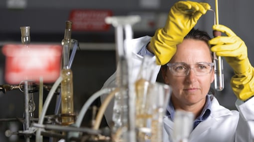 mujer con lentes de seguridad llevando a cabo un experimento de laboratorio