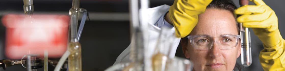 mujer con lentes de seguridad llevando a cabo un experimento de laboratorio