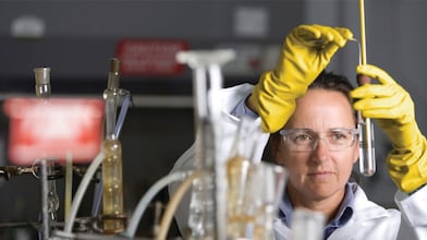 mujer con lentes de seguridad llevando a cabo un experimento de laboratorio