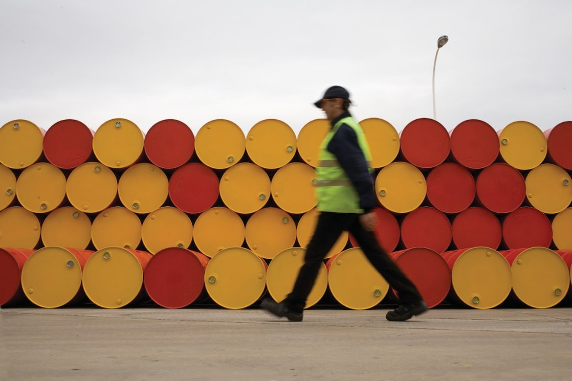 hombre caminando al lado de barriles de lubricantes