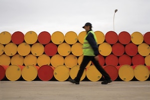 hombre caminando al lado de barriles de lubricantes