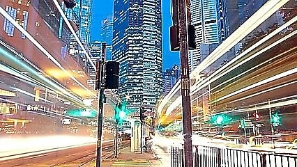 A city scape at night with trailing lights from cars going by.