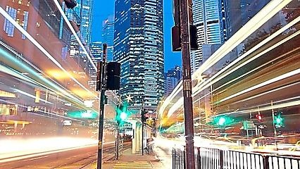 A city scape at night with trailing lights from cars going by.