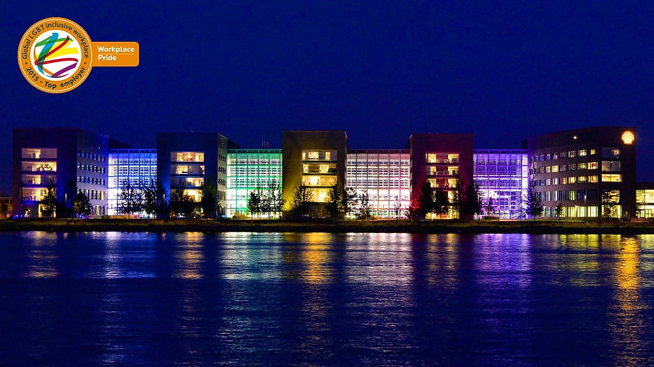 A set of lit office buildings reflect off the water at night