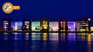 A set of lit office buildings reflect off the water at night