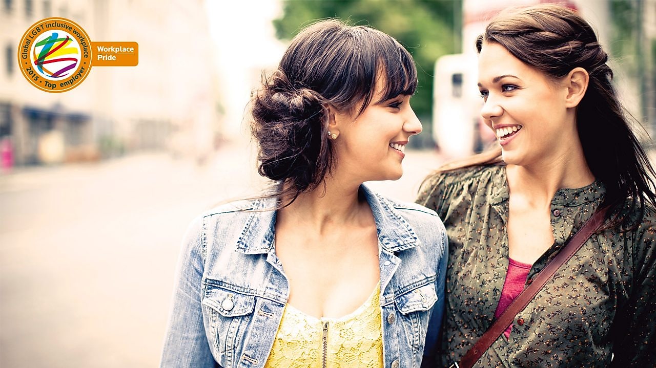 Two girls smile at each other as they walk down the street
