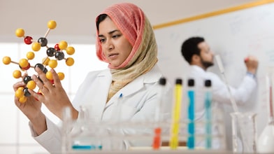 mujer con hijab examinando modelo molecular