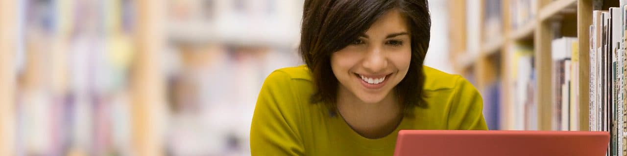 mujer con laptop en una librería sonriendo