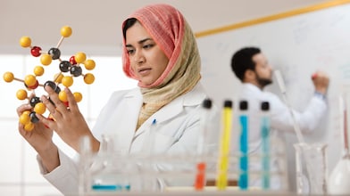 mujer con hijab examinando modelo molecular
