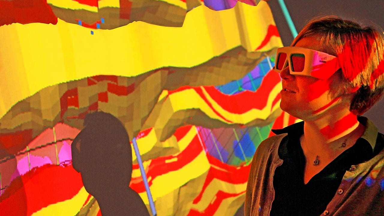 Una mujer con gafas especiales examina una proyección en 3D de un mapa geológico 