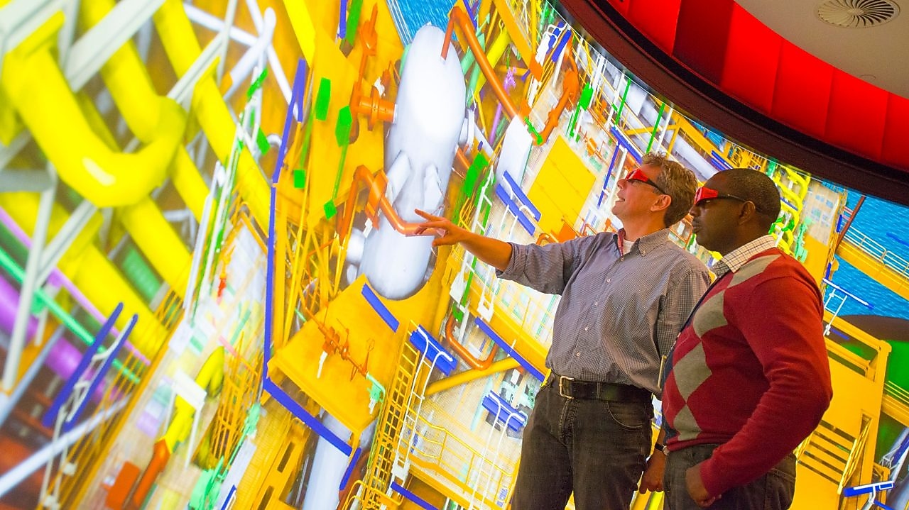 Dos hombres utilizan gafas en 3D para mirar a una pantalla en color de gran tamaño