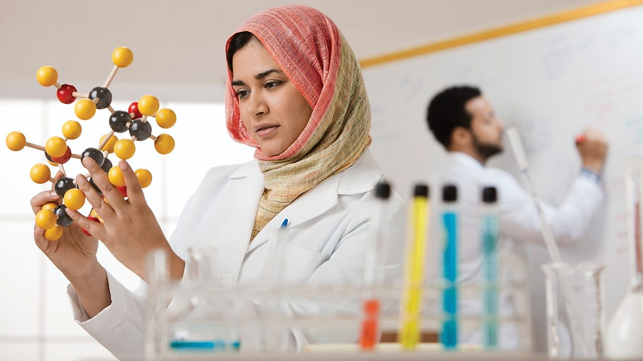 mujer con hijab examinando modelo molecular
