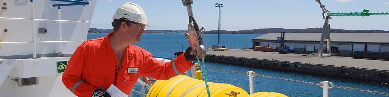 Empleado inspeccionando un equipo en un barco atracado
