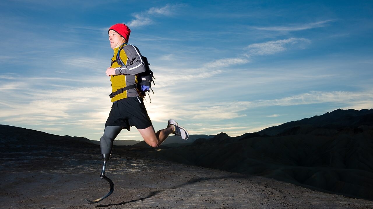 atleta masculino con pierna ortopédica corriendo en el monte