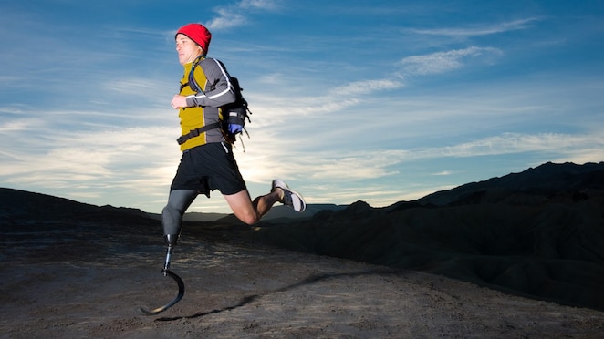 man with prosthetic leg, in running clothes, running in the hills in the early morning