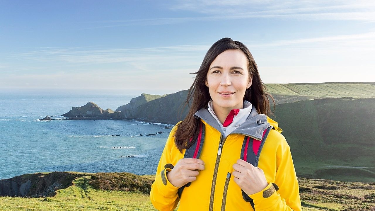 Mujer de pie en la montaña con unas bolsas