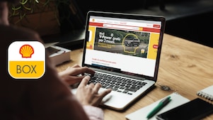 Computadora abierta sobre un escritorio y persona de espaldas tipeando sobre el teclado.