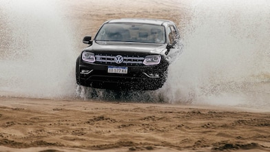 camioneta volkswagen negra surcando el agua velozmente