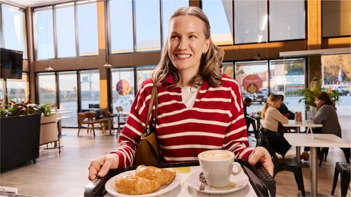 Mujer sosteniendo una bandeja con café y medialunas.9
