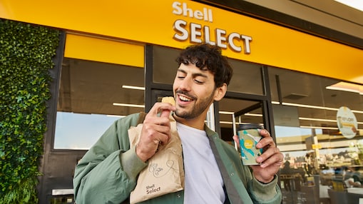 Hombre saliendo de Shell Select con medialuna y café