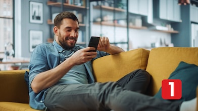Hombre usando el celular en el sillón de su casa.