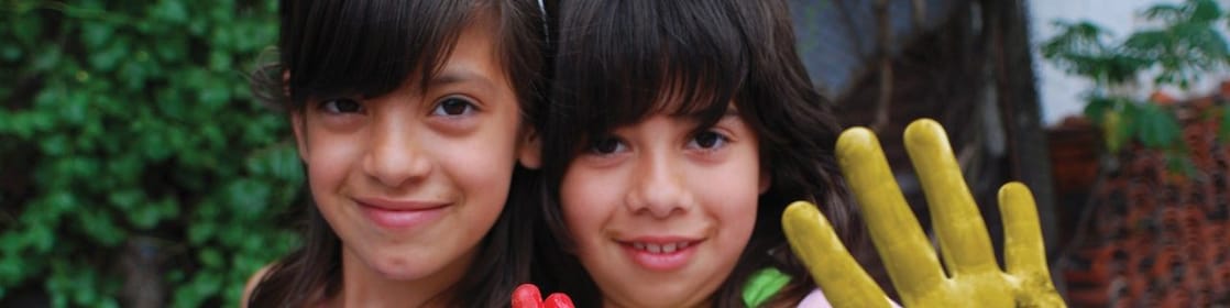 Dos niñas mostrando sus manos cubiertas de témpera
