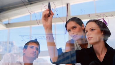 Mujer de negocios dibujando gráficos en una pizarra transparente