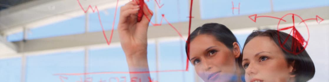 Mujer de negocios dibujando gráficos en una pizarra transparente